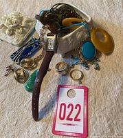 Overall shot of assorted jewelry pieces and porcelain trinket box components on cloth surface.