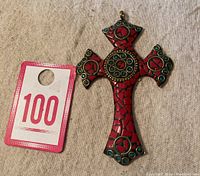 Brass cross pendant with coral and turquoise mosaic shown next to a numbered tag for size reference.