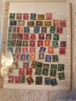 Photo of a single album page showing approximately 70 old Canadian postage stamps of various denominations and colors affixed.