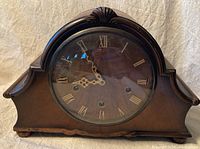 Front view of vintage Smiths Enfield mantel clock with wooden case and Roman numeral dial under glass.