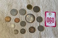 Top down photo capturing all 15 coins showing various sizes, metals and designs with auction tag 060.