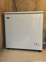 Front view of white chest freezer showing mechanical thermostat control on bottom right front panel.