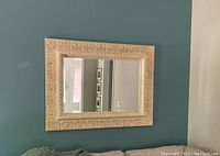 Full view of the rectangular accent wall mirror mounted on blue-green wall above couch.