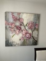 Front-facing view of square canvas print showing cherry blossom branches with pink flowers and green leaves against neutral grayed background.