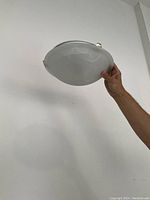 Photo showing the white marbled glass dome flushmount light held against a plain white wall, highlighting the shallow dome shape and smooth glass surface.