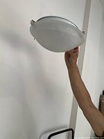 Side angle of the flushmount light fixture showing the white marbled glass dome held by three pewter clips.