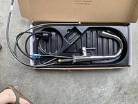 Photo of Delta Essa pull-down kitchen faucet in its box showing faucet body, handle, spout and attached hoses.