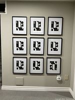 Nine black gallery frames mounted on a wall in a 3x3 grid, each containing a black and white abstract print, showing the product setup and condition.