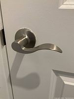 Curved satin nickel lever handle mounted on white door showing finish and style