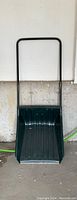 Full front view of the sleigh snow shovel showing the large green plastic scoop and black rectangular steel handle.