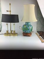 Both vintage table lamps displayed side by side on white surface with ruler and decorative item beside them.