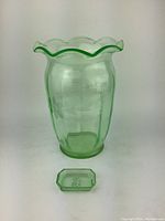 Front view of uranium glass vase and small etched dish showing green glowing color and floral etching on vase.