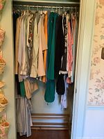 Closet view showing a variety of vintage ladies clothing, mostly tops, hung on hangers. Mostly small and medium sizes with varied colors and fabrics visible.