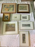 Eight original framed artworks laid flat on a white cloth, showing various scenes including flora and landscapes