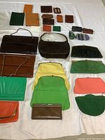 Full view of all purses, wallets, and bags laid out on white surface showing sizes, styles, and colors