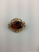 Front view of brooch showing oval citrine and surrounding pearls in gold filigree setting
