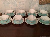 Eight tea cups and matching saucers arranged on a surface, showing the complete set for 8 people.