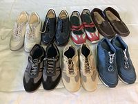 Top view of all 7 pairs of ladies Rockport shoes arranged in two rows showing a variety of colors including beige, black, red/white, brown, tan, and blue in lightly used condition.