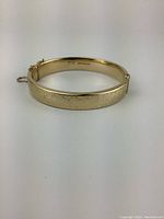 Front view of the hinged gold bangle showing etched exterior