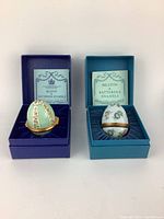Two Bilston and Battersea enamel eggs in original blue velvet-lined boxes with certificates.