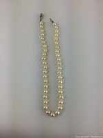 Full-length view of strand showing uniform round pearls and clasp position