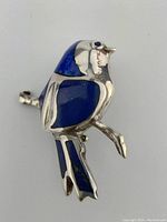 Close-up front view of sterling silver bird brooch with blue lapis stone insets on wings and head.