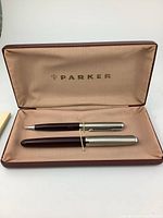 Both pens displayed inside the Parker-branded case showing the satin lining and the pens' design.