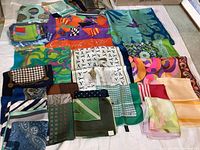 Overview of 16 folded square silk scarves in assorted patterns