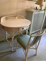 Side angle showing the white wicker table with solid wood white oval top and pale blue cushioned wicker chair