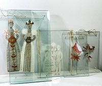 Front view of all glass-framed needlework pieces including two figures and three birds.
