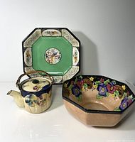 Full view of teapot, bowl, and plate with floral and bird motifs.