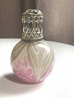 Glass fragrance lamp showing swirled pink, white, and pale brown patterns with silver metal lattice top.