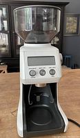White Breville coffee grinder with clear bean hopper, digital control panel, and grind size dial.
