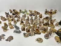 Wide shot of over 60 ceramic figurines in various animal shapes arranged on a white surface