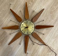 Full view of the sunburst wall clock showing overall design and wood rays with metal rods.