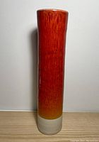 Full view of the tall cylindrical vase showing the color gradient from deep red at the lip transitioning to orange and then natural beige at the base.