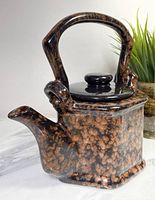 Photo showing front and left side view of mottled ceramic teapot with loop handle and spout.