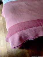 Overall view of the pink wool blanket showing color and texture against a wooden floor