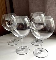 Four Waterford Marquis balloon wine glasses arranged on a white surface, showing full set.