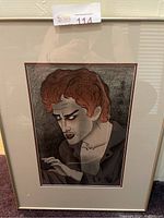 Framed artwork showing a character with reddish curly hair and intense facial expression, signed with Japanese script.