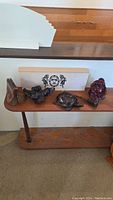 Four wooden hand-carved Indigenous items displayed on wooden stand shelf including raven spirit box, sea turtle, Buddha, and mountain carving.