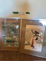 Both Japanese woodblock prints framed and leaning against the wall