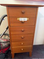 Front view of the dresser with closed drawers, showing wooden knobs and damage to top surface.
