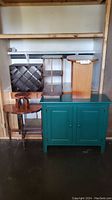 Image shows the set of six furniture pieces including teal cabinet, wooden half moon table, small wooden stand, magazine and wine racks.