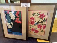 Full view of two framed Japanese artworks, floral themes, one with chrysanthemums and one with pink flowers and a bird.