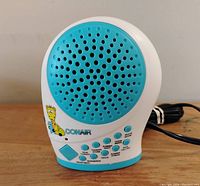 Front view of Conair sound machine showing speaker grill, giraffe logo, control buttons and power cord.