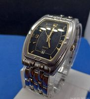 Front angled view showing metal case and linked band, dial with gold numerals and date window.