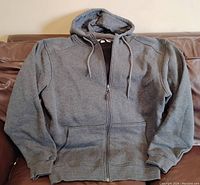 Full view of the grey lined hoodie spread out on a surface, showing front zipper and pockets.