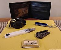 Overall view of the men's leather wallet along with the included multi-tools, compass, clippers, and Birks pocket tool with English setter dog image