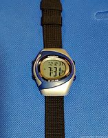 Front view of Umbro digital sport watch on blue fabric background, showing time 7:31 and date Tuesday 12-31.
